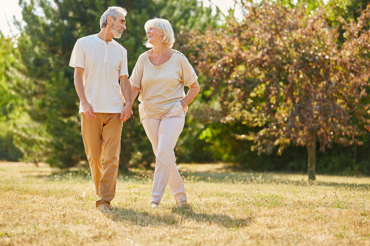 Pareja de ancianos sanos caminando al aire libre.
