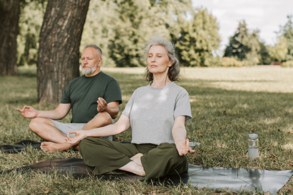 Pareja sana y madura que reduce el estrés meditando en la naturaleza.
