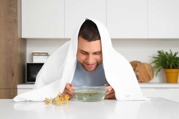 Tratamiento de la gripe, un hombre inhala vapor de un recipiente en la cocina.