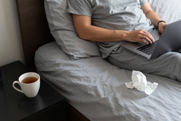 Persona que trabaja desde casa mientras se recupera de la gripe.
