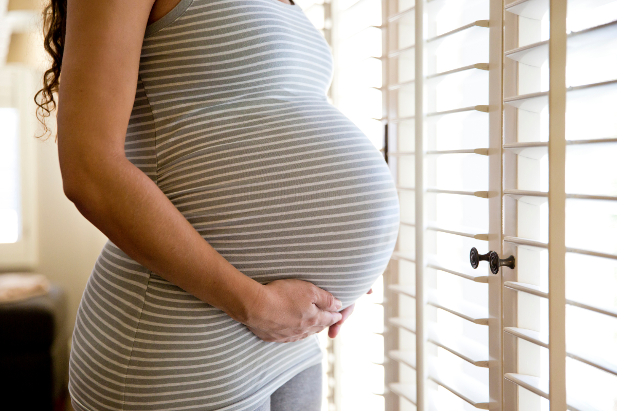 Mujer sosteniendo su gran barriga de embarazada con las manos.