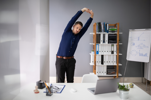 Un hombre tomándose un descanso de su computadora para hacer algunos estiramientos laterales.